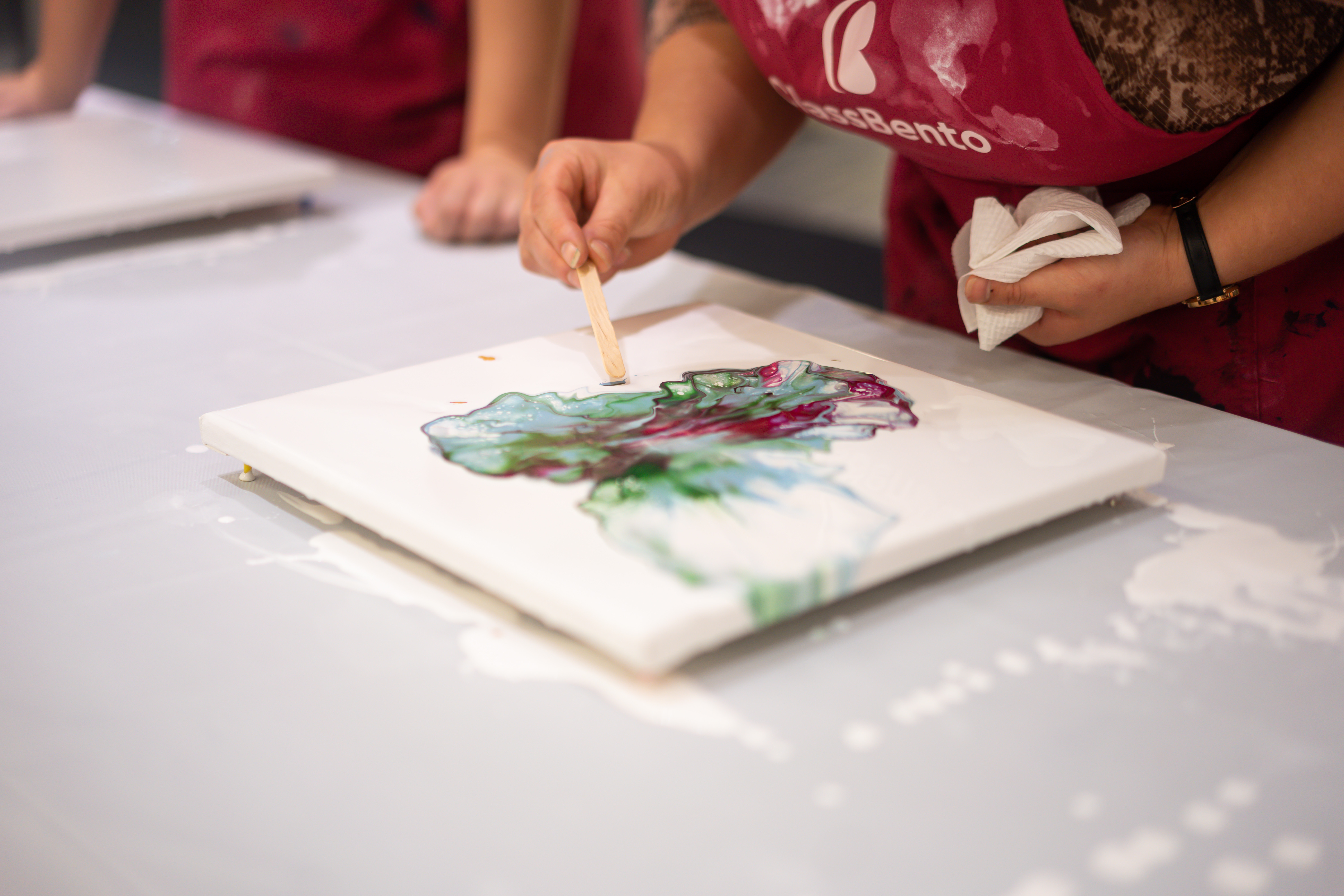 Hands using paint in a paint pouring abstract art class